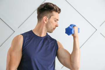 Sticker - Sporty young man with dumbbell on light background