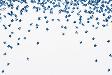 Wall Mural - iridescent star shape confetti on white. classic blue color holiday background. glowing sparkles fra