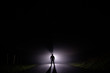 Silhouette of a man in the darkness. Night Photography. Bright light shining behind dark mysterious figure. Ghostly, mystical, surreal person standing.