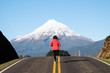 Woman running on a straight road toward mountain. Motivation determined inspiration endurance concept 