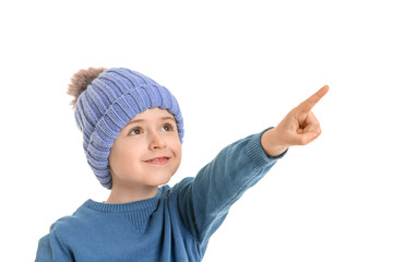 Cute little boy in winter clothes pointing at something on white background