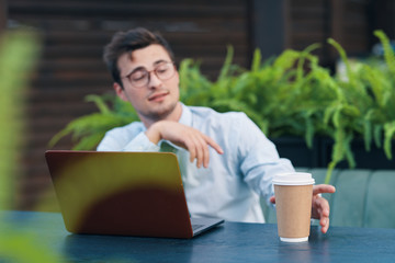 Poster - young man sitting on sofa and working on her laptop