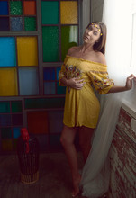 1960's Inspired Concept Shoot Features Beautiful Brunette Woman In Yellow Print Dress And Headband - Standing In Front Of Multicolored Stained Glass Wall