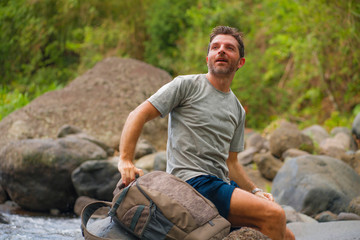 young happy and attractive man with travel backpack hiking in river at forest feeling free enjoying nature and fresh environment on summer trekking journey