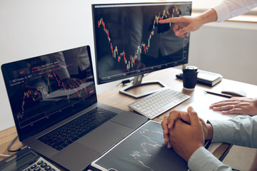 Two partnership investors discussion working together are analyzing the stock chart on the computer screen at the office company.