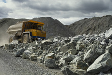 Heavy Mining Dump Truck In A Limestone Quarry With Huge Fragments Of Rock In The Foreground. Quarry Equipment. Mining Industry.