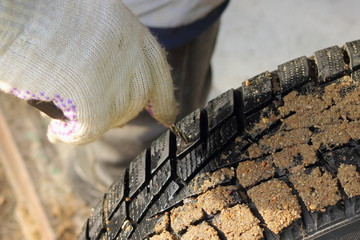 Wall Mural - Repairman hand in a work glove search with an awl a puncture on the car punctured tire close up, outdoor tyre repair on road