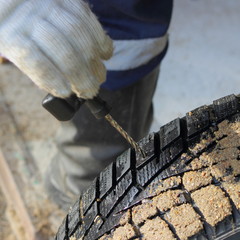 Wall Mural - A hand in a work glove cleans the wheel puncture with an awl