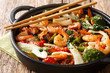 One pot stir fried shrimp, squid and mussels with fresh vegetables close-up in a pan on the table. horizontal