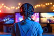 © Anton - Gamer or streamer girl at home in a dark room playing video games with friends online. A young man sits in front of three monitors