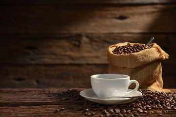 Wall Mural - Cup of coffee and coffee beans on old wooden background