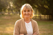 © ztony1971 - Portrait shot of happy, successful, relax caucasian senior woman smiling with a carefree look toward the camera at the park as a background with copy space in natural autumn sunlight.