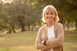 © ztony1971 - Portrait shot of happy, successful, relax caucasian senior woman smiling with a carefree look toward the camera at the park as a background with copy space in natural autumn sunlight.
