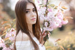 © ElenaBatkova - Portrait of a beautiful young woman model near pink branches with Sakura flowers.