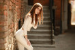 © ElenaBatkova - Beautiful model in white stretch clothes on urban brick wall background closeup.