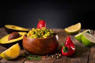 Spicy gucamole bowl dip with peppers, avocado and lemon