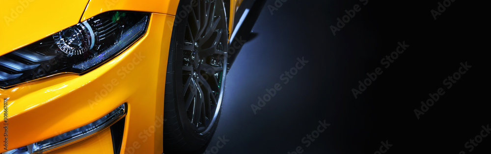 Front headlights of yellow modern car on  black background,copy space - obrazy, fototapety, plakaty 