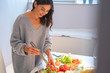Smiling lady in the kitchen with salad tweezers stock photo
