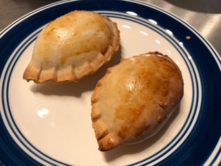 Two thick empanada rolls, a pastry snack with meat and vegetable stuffing