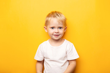 2 years portrait of little blond happy caucasian blue eyes baby boy wearing on white t shirt on yell