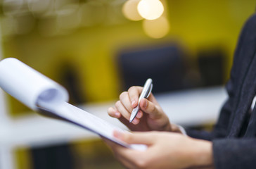 A man signs a contrac, legal or business agreements. Male hand with pen of young office worker makes notes. Business man  sitting at office desk and signing a document in modern office.