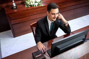 Wall Mural - Receptionist in black suit sitting and working