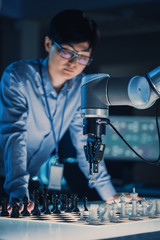 Leinwandbilder - Vertical Shot of a Professional Japanese Development Engineer Testing an Artificial Intelligence Interface by Playing Chess with a Futuristic Robotic Arm. High Tech Modern Research Laboratory.