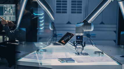 Leinwandbilder - Futuristic Artificial Intelligence Robotic Arm Operates and Moves a Metal Object, Picks It Up or Puts it Down. High Tech Research Laboratory with Modern Equipment.