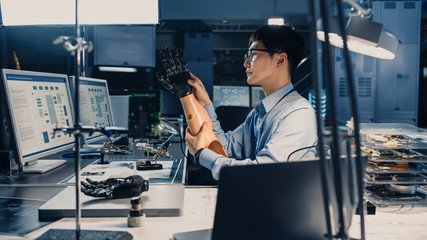 Fototapete - Futuristic Prosthetic Robot Arm Being Tested by a Professional Japanese Development Engineer in a High Tech Research Laboratory with Modern Computer Equipment. He is Satidfied with the Result.