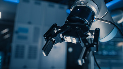 Leinwandbilder - Close Up of a Futuristic Robotic Arm Moving a Metal Object and Placing It. Team of Engineers Observe This Advanced Process. They are in a High Tech Research Laboratory with Modern Equipment.
