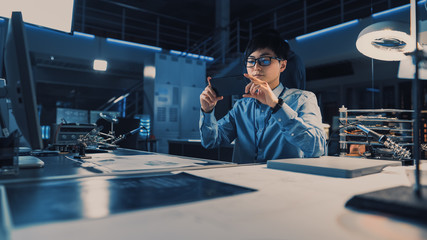 Leinwandbilder - Professional Japanese Development Engineer in Blue Shirt Taking a Photo of Technical Drawings on His Smartpgone in the High Tech Research Laboratory with Modern Computer Equipment.