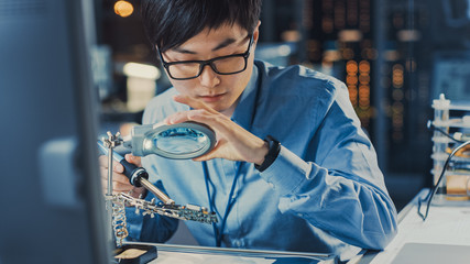 Leinwandbilder - Close Up of a Professional Japanese Electronics Development Engineer in Blue Shirt Soldering a Circuit Board in a High Tech Research Laboratory with Modern Computer Equipment.