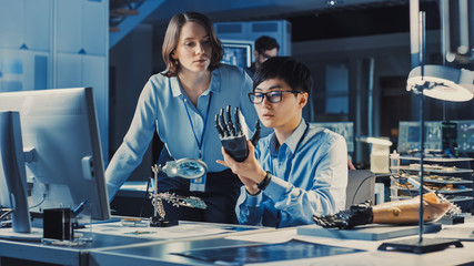 Leinwandbilder - Technological Prosthetic Robot Arm is Closely Tested by Two Professional Specialists in a High Tech Research Laboratory with Modern Futuristic Equipment. Man and Female Talk and Ananlyse the Object.