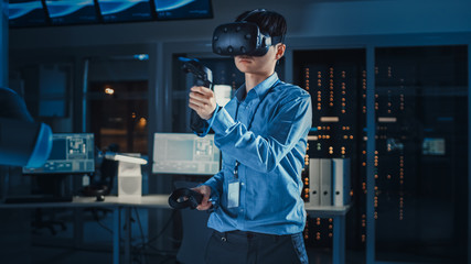 Leinwandbilder - Professional Japanese Development Engineer in Blue Shirt is Using Augmented Reality Headset and Joysticks in a High Tech Research Laboratory with Modern Equipment.