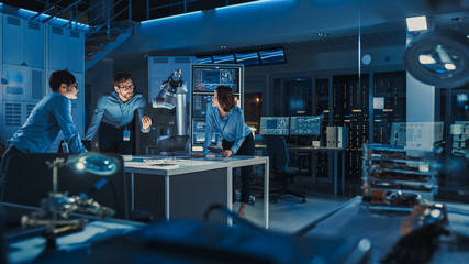 Leinwandbilder - Futuristic Metal Robotic Arm is Moving a Metal Object. Senior Engineer Talks Through This Advanced Process with His Diverse Team. They are in a High Tech Research Laboratory with Modern Equipment.