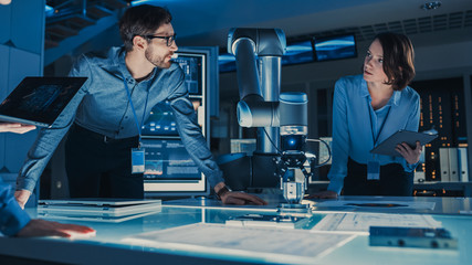 Leinwandbilder - Diverse Team of Engineers with Laptop and a Tablet Analyse and Discuss How a Futuristic Robotic Arm Works and Moves a Metal Object. They are in a High Tech Research Laboratory with Modern Equipment.