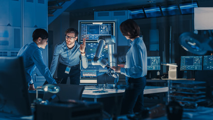 Leinwandbilder - Diverse Team of Engineers with Laptop and a Tablet Analyse and Discuss How a Futuristic Robotic Arm Works and Moves a Metal Object. They are in a High Tech Research Laboratory with Modern Equipment.