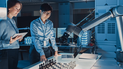 Fototapete - Two Development Engineers are Discussing and Testing an Artificial Intelligence Interface by Playing Chess with a Futuristic Robotic Arm. They are in a High Tech Modern Research Laboratory.