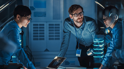 Leinwandbilder - Diverse Team of Engineers with Laptop and a Tablet Analyse and Discuss How a Futuristic Robotic Arm Works and Moves a Metal Object. They are in a High Tech Research Laboratory with Modern Equipment.