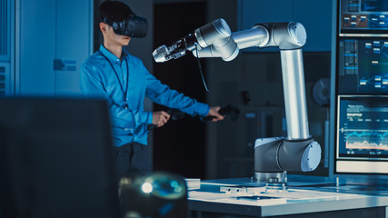 Poster - Professional Japanese Development Engineer in Blue Shirt is Controlling a Futuristic Robotic Arm with a Virtual Reality Headset and Joysticks in a High Tech Research Laboratory with Modern Equipment.