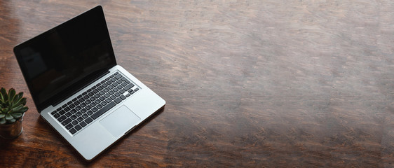 Laptop with black blank screen on a wooden desk