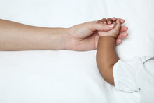 Mother Hand Holding Baby Girl Hand On White Bed