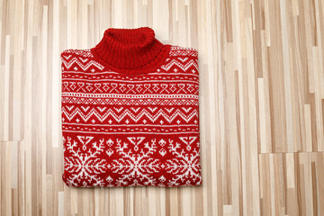 Wall Mural - Red knitted Christmas turtleneck sweater with nordic ornament folded on wooden background