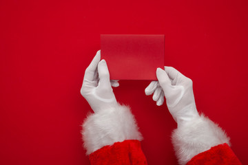 Wall Mural - Father Christmas holding a red blank card. Overhead view