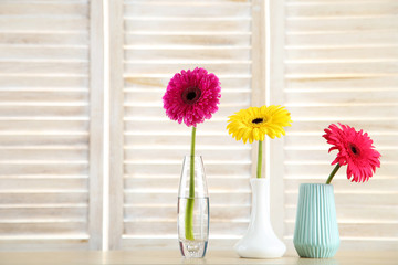 Wall Mural - Ceramic vases with gerbera flowers on wooden background