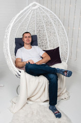 Cute sporty man in chair near the Christmas tree