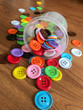 Button beads are blue, green, yellow, pink, white, purple. The background is poured on the table.