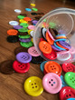 superb Button beads are blue, green, yellow, pink, white, purple. The background is poured on the table.
