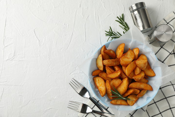 Wall Mural - Plate of sliced baked potato wedges, rosemary, salt, forks on white background, top view. Space for text