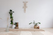 © Rithor - Wicker rug is lying on wooden floor next to pots with plants and hanging on the wall with wicker macrame on a white background. Concept is a cozy place in the house for classes. Advertising space